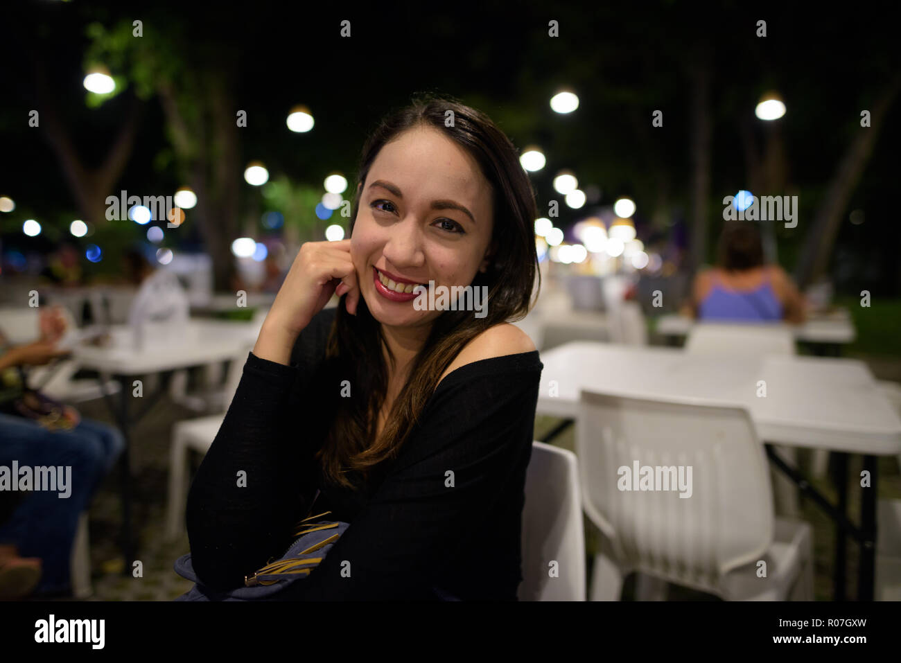 Giovani felici bella asiatica donna sorridente mentre è seduto al n Foto Stock