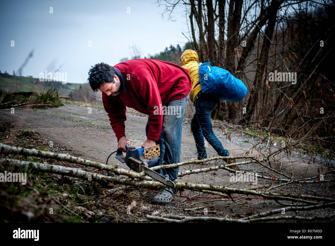 Uomo che utilizza un chainsaw senza alcuna protezione ingranaggio molto precarie condizioni di salute e di sicurezza. Foto Stock