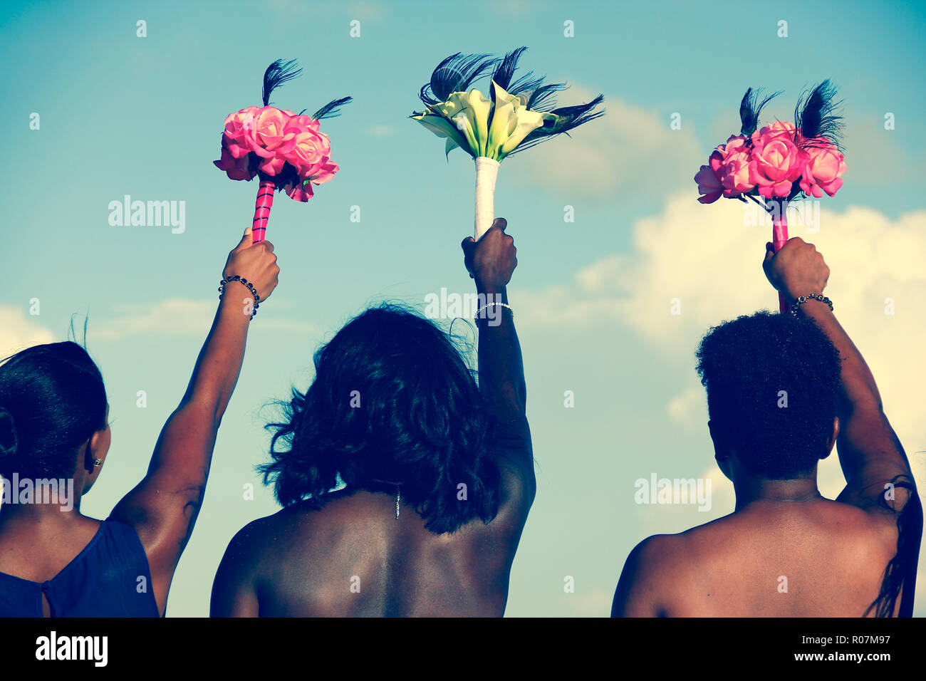 Retro del americano africano donne azienda mazzi di fiori colorati in aria il giorno del matrimonio. Sposa e le cameriere di onore fiori in salita verso il cielo Foto Stock