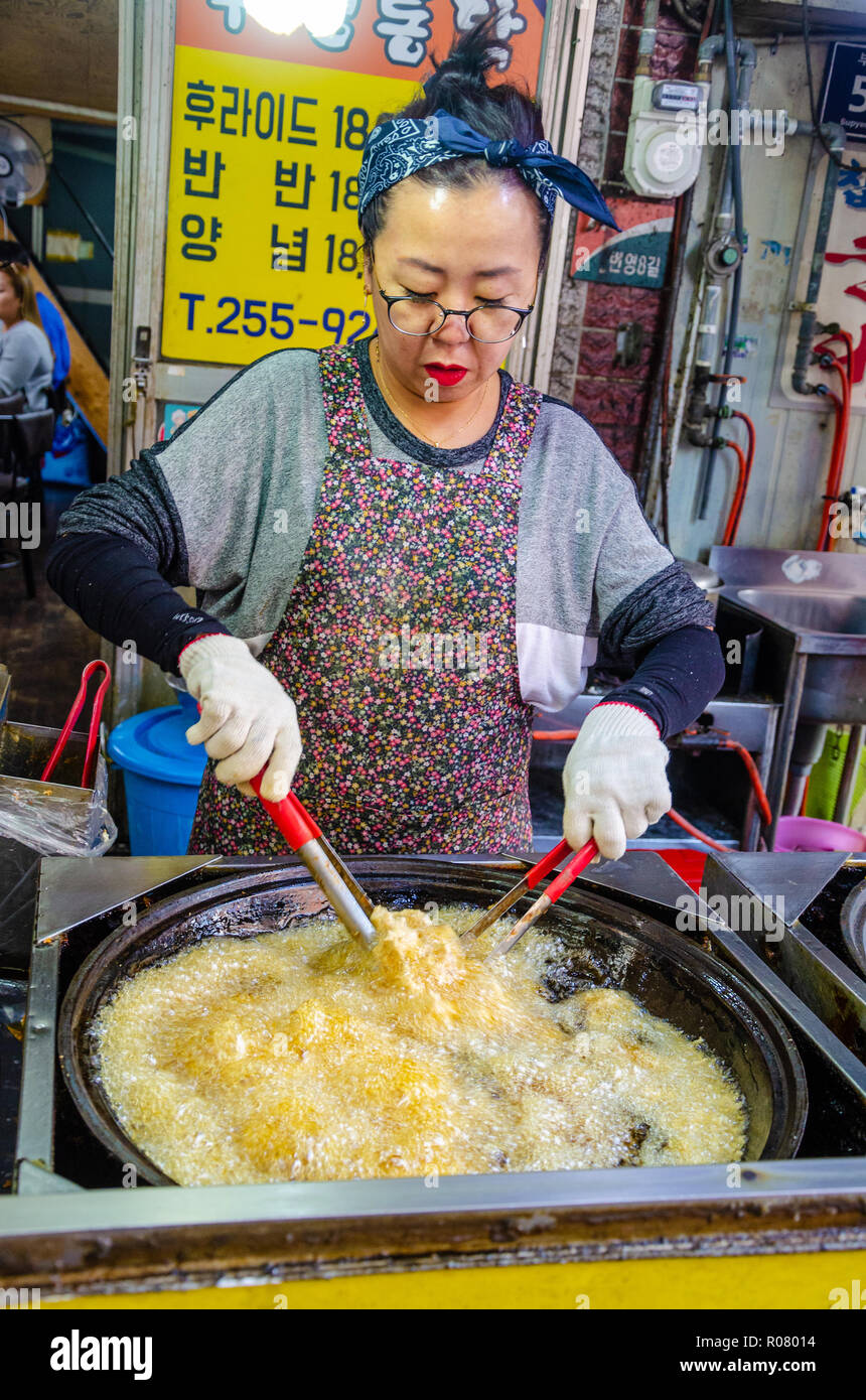 Un coreano lady cuochi fritto di pollo di Bupyeong Kkangtong Mercato in Busan, Corea del Sud. Il pollo fritto è un popolare, a buon mercato e una gustosa cucina di strada. Foto Stock