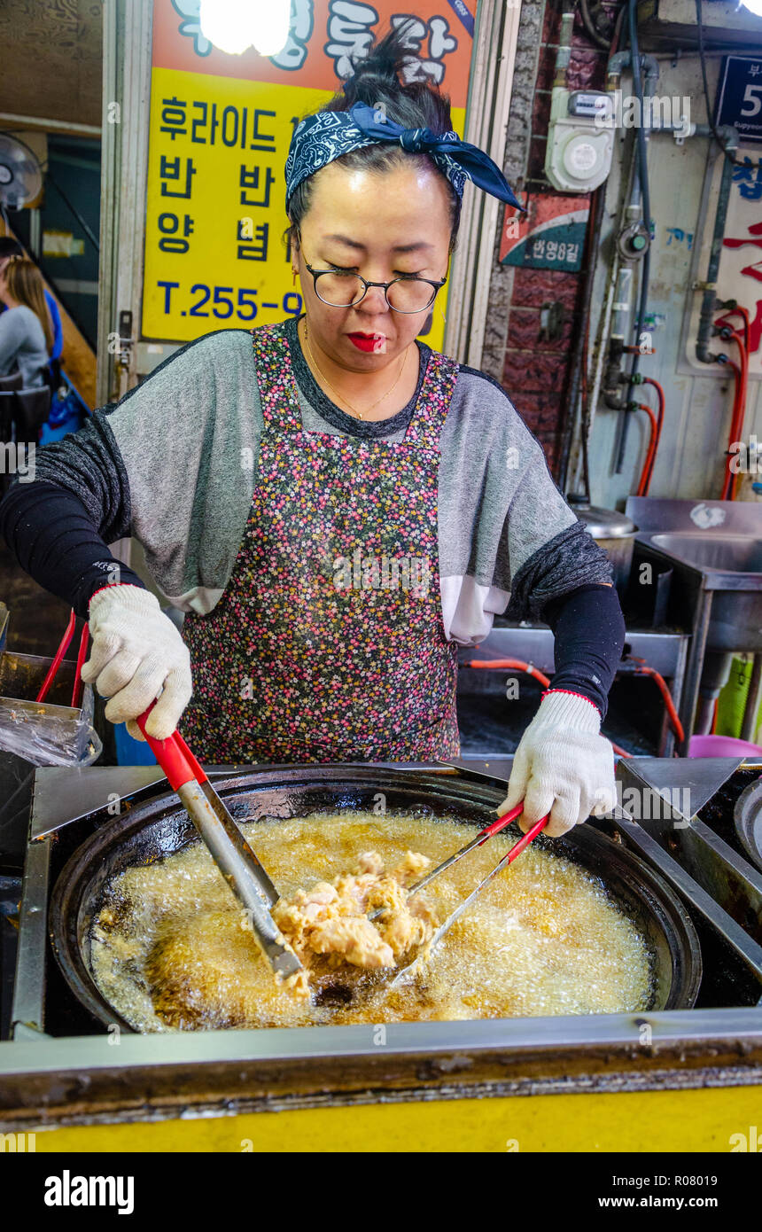 Un coreano lady cuochi fritto di pollo di Bupyeong Kkangtong Mercato in Busan, Corea del Sud. Il pollo fritto è un popolare, a buon mercato e una gustosa cucina di strada. Foto Stock