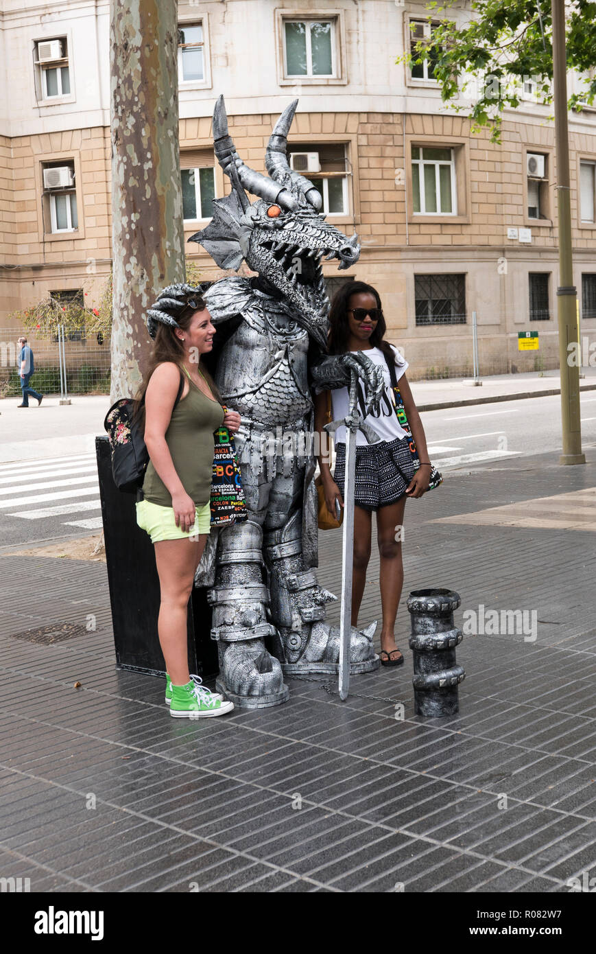 L'artista di strada in costume del drago di essere fotografato con due donne Las Ramblas, Barcelona, Spagna Foto Stock