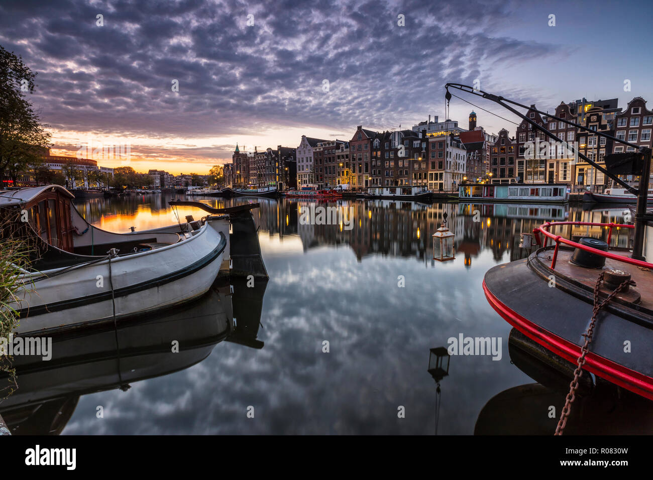 Amsterdam sunrise, case illuminate e barche di riflessione di acqua Foto Stock