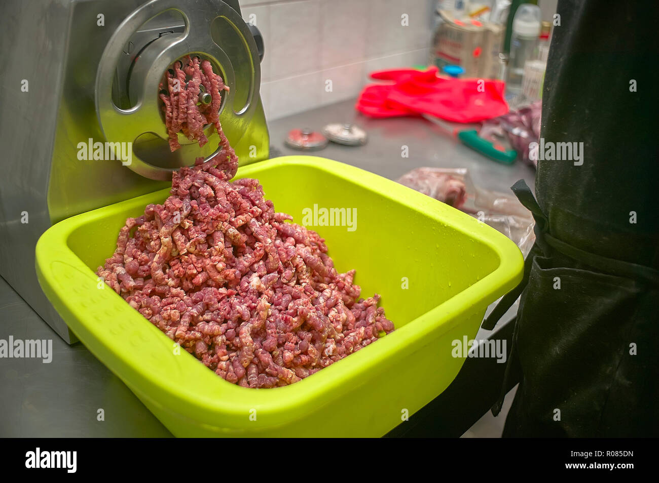 Macchina per macinare la carne in azione durante il riempimento di un  contenitore di carni macinate pronto per l'uso Foto stock - Alamy