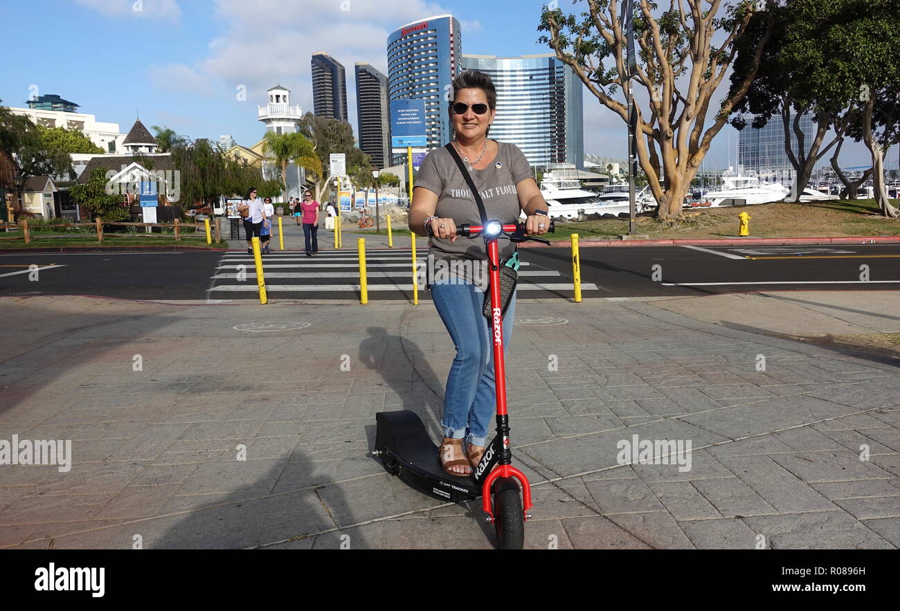 Un turista femminile per divertirsi in sella ad una dockless elettrico scooter nel centro cittadino di San Diego Foto Stock