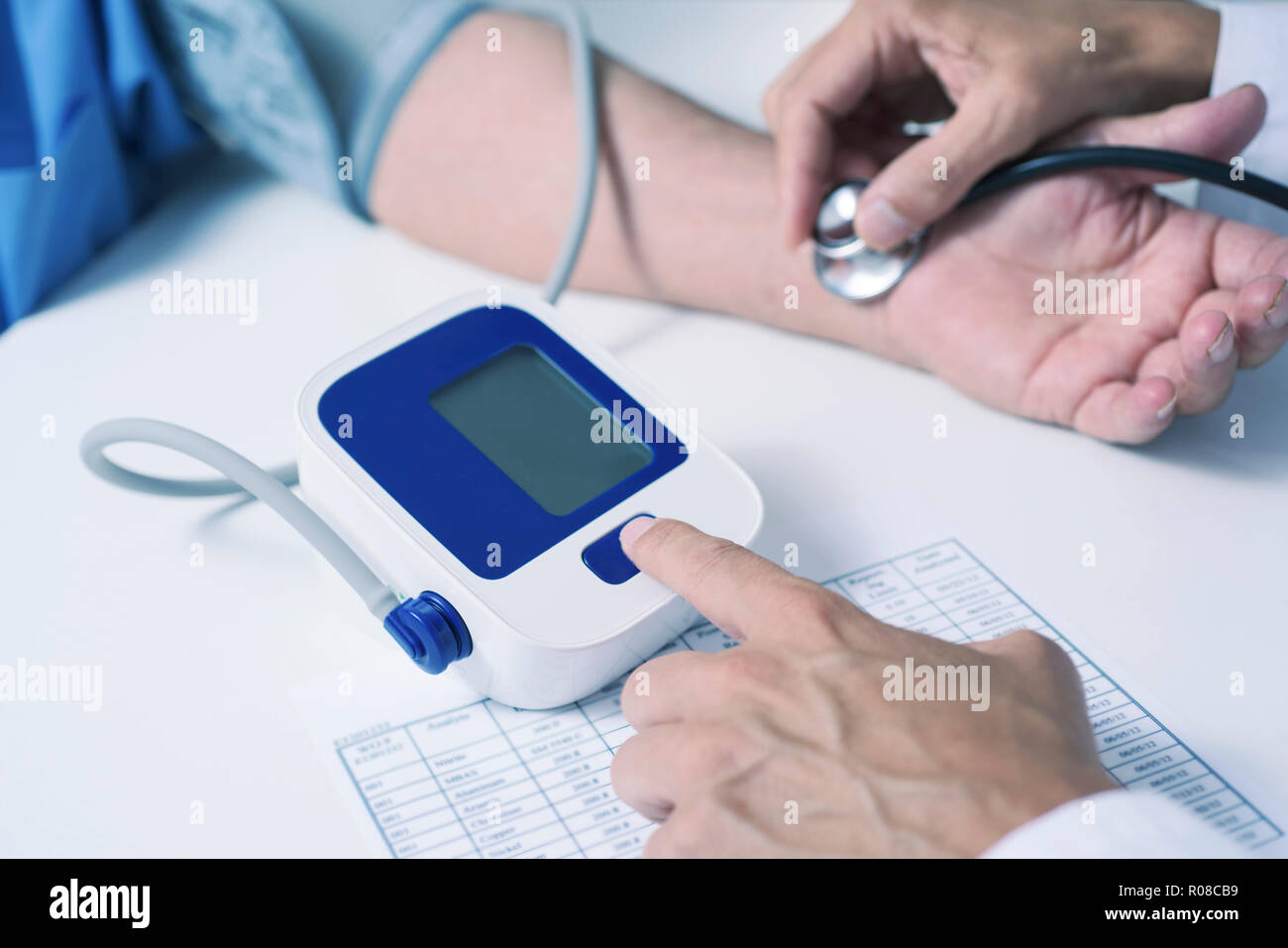 Primo piano di un medico caucasica uomo in camice bianco, la misurazione della pressione del sangue di un senior caucasica uomo paziente con uno sfigmomanometro Foto Stock