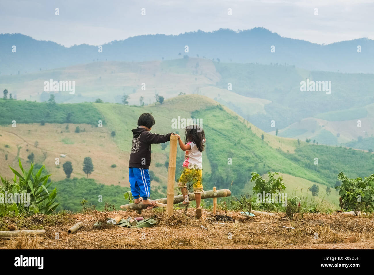 Nan, Thailandia. Ottobre 20,2014 : Thai ragazze stanno giocando su un attrezzo di bambù con le montagne sullo sfondo. Foto Stock