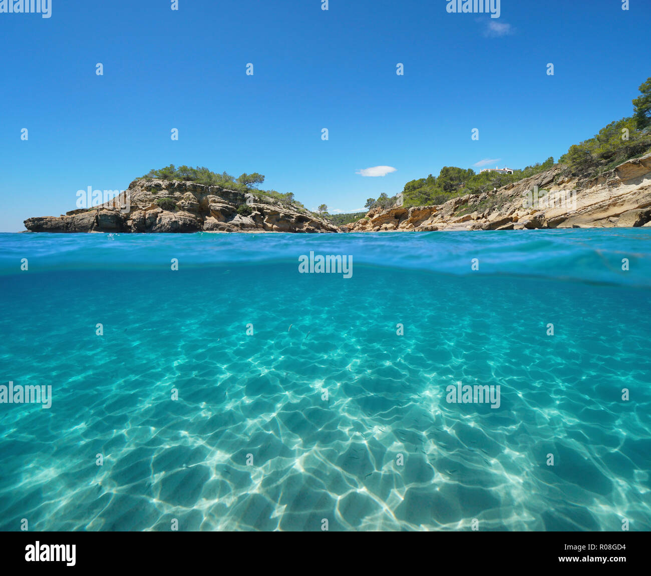 Costa rocciosa con un isolotto e sabbia subacquea, vista suddivisa per metà al di sopra e al di sotto della superficie dell'acqua, il mar Mediterraneo, l'Illot, L'Ametlla de Mar, Spagna Foto Stock
