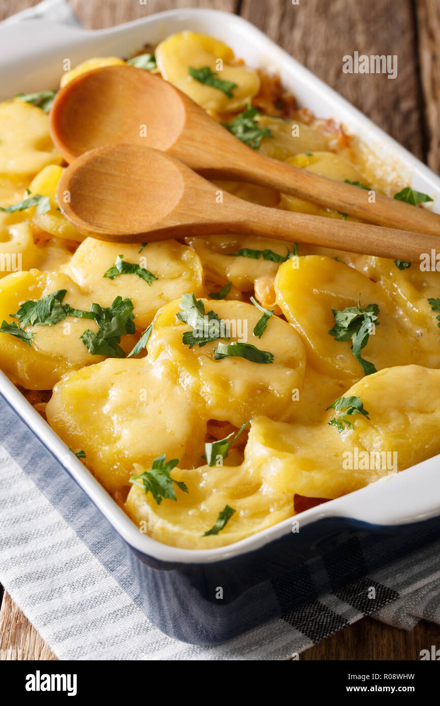La cucina tedesca: crauti casseruola con patate, pancetta e formaggio close-up in una teglia sul piano verticale. Foto Stock