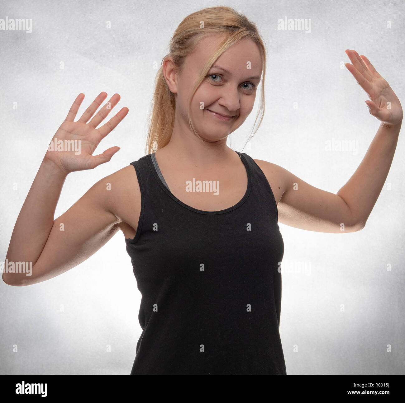 Giovane donna in nero serbatoio superiore con entrambe le mani aperte Foto Stock