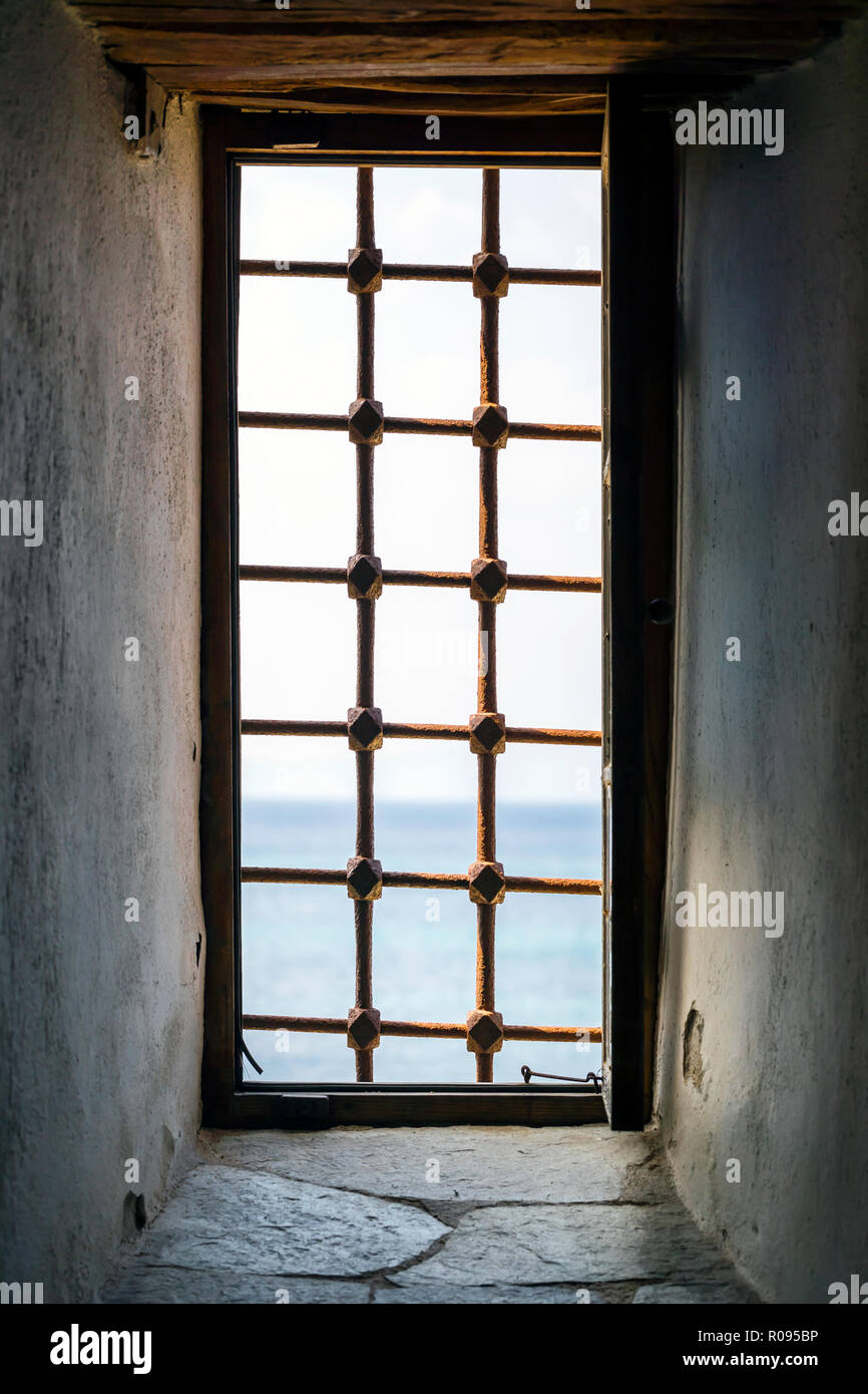 Vecchia finestra con barre di metallo in un antico edificio di pietra Foto Stock