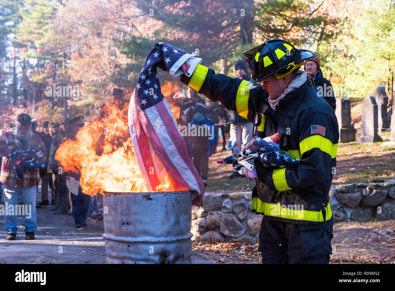 Concord pompiere attentamente tenendo una bandiera sulle fiamme a bandiera annuale cerimonia di pensionamento. Foto Stock
