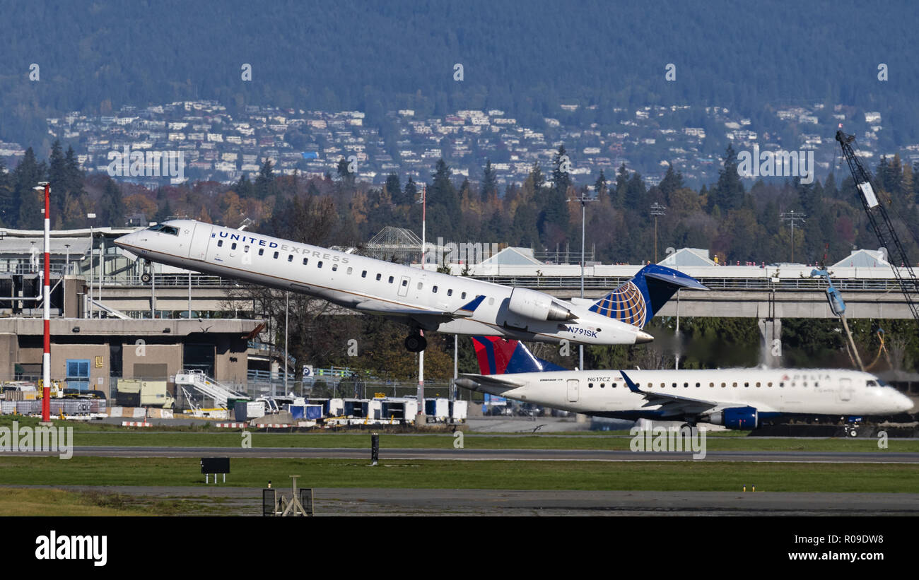 Richmond, Canada. Il 2 novembre 2018. Un regno Express Bombardier CRJ-700 (N791SK) stretto in corpo unico regionale del corridoio aereo jet decolla dall'Aeroporto Internazionale di Vancouver. L'aereo di linea è di proprietà e gestito da SkyWest Airlines sotto contratto con la United Airlines. Sullo sfondo di un Delta Connection (Compass Airlines) Embraer 175 taxi per assumere la posizione off. Credito: Bayne Stanley/ZUMA filo/Alamy Live News Foto Stock