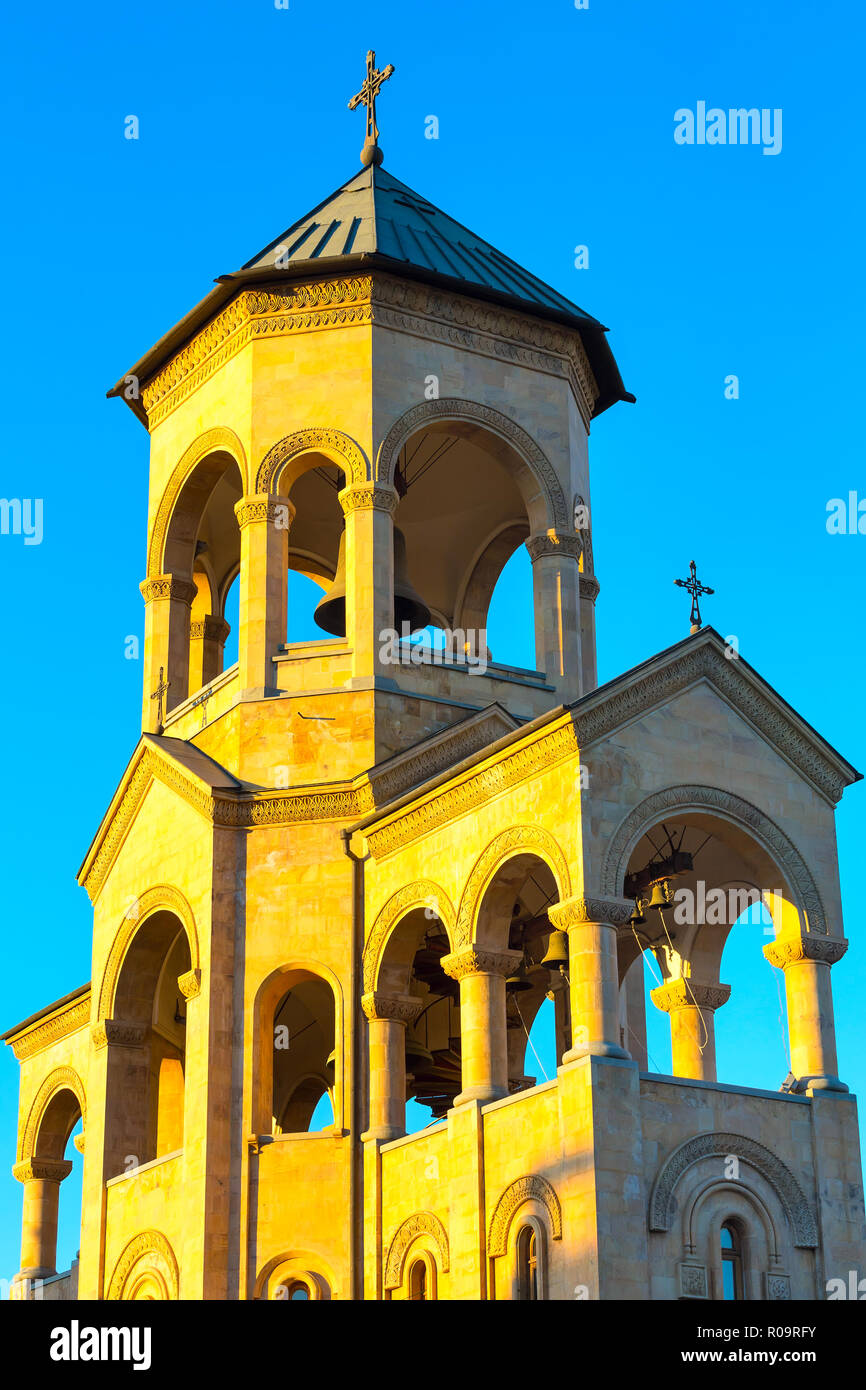 Campanile vicino alla chiesa della Santa Trinità o Tsminda Sameba Cattedrale al tramonto a Tbilisi, Georgia Foto Stock
