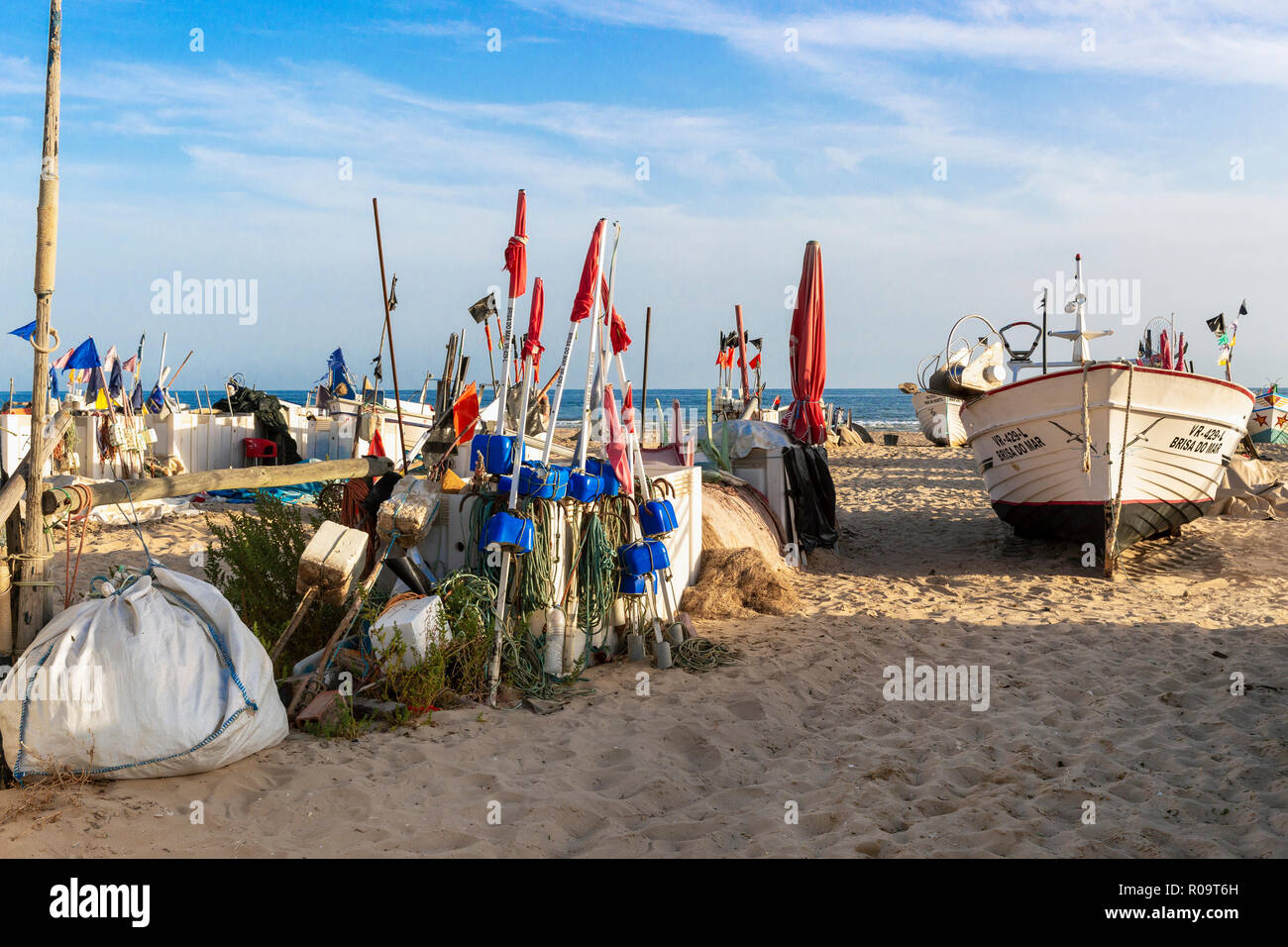 Locali di pesca in barca circondato da galleggianti di pesca sulla spiaggia di Monte Gordo, Algarve, Portogallo la sera sun Foto Stock