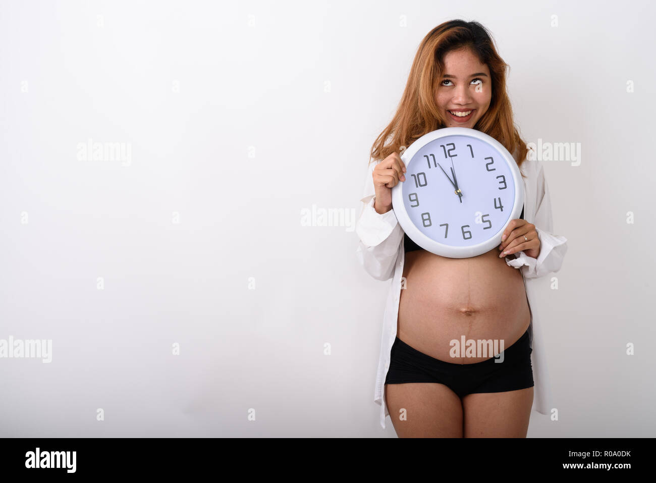 Ritratto di giovane e bella incinta donna asiatica holding orologio Foto Stock