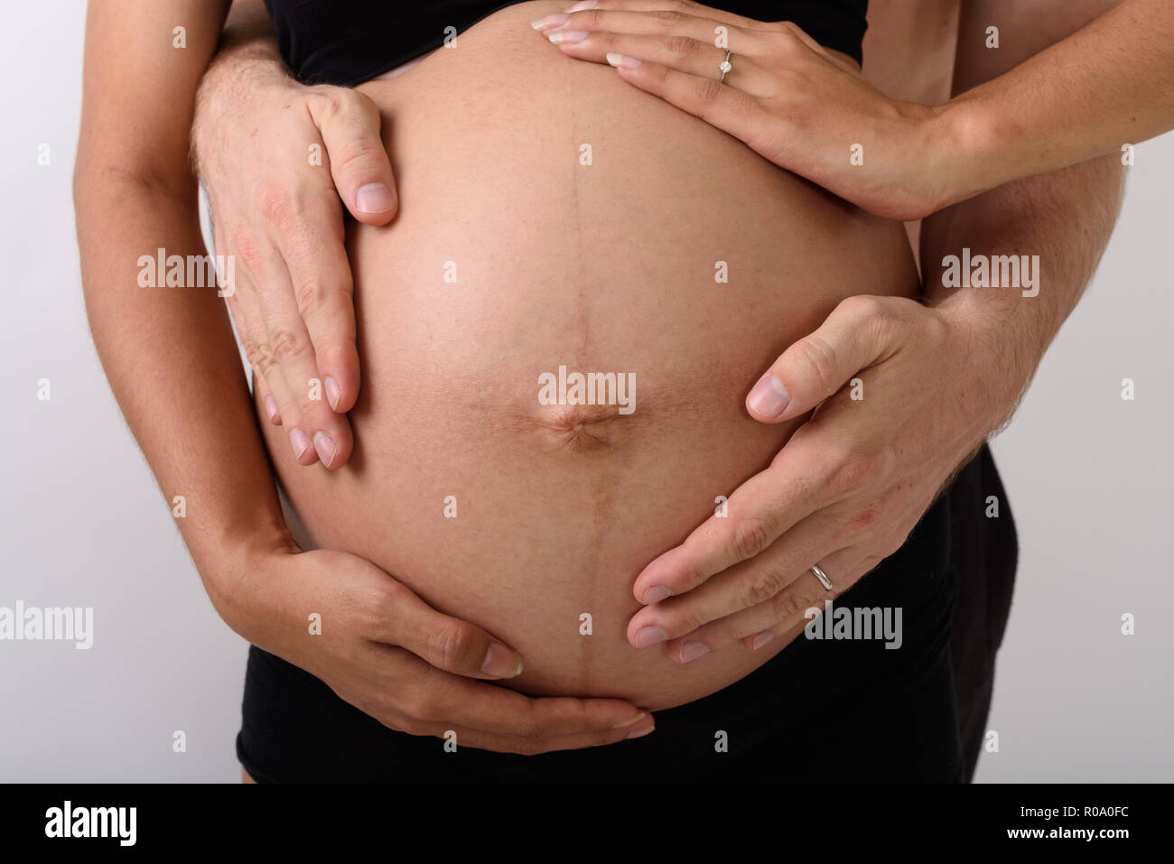 Asian donna incinta con l uomo mentre tiene il suo stomaco Foto Stock