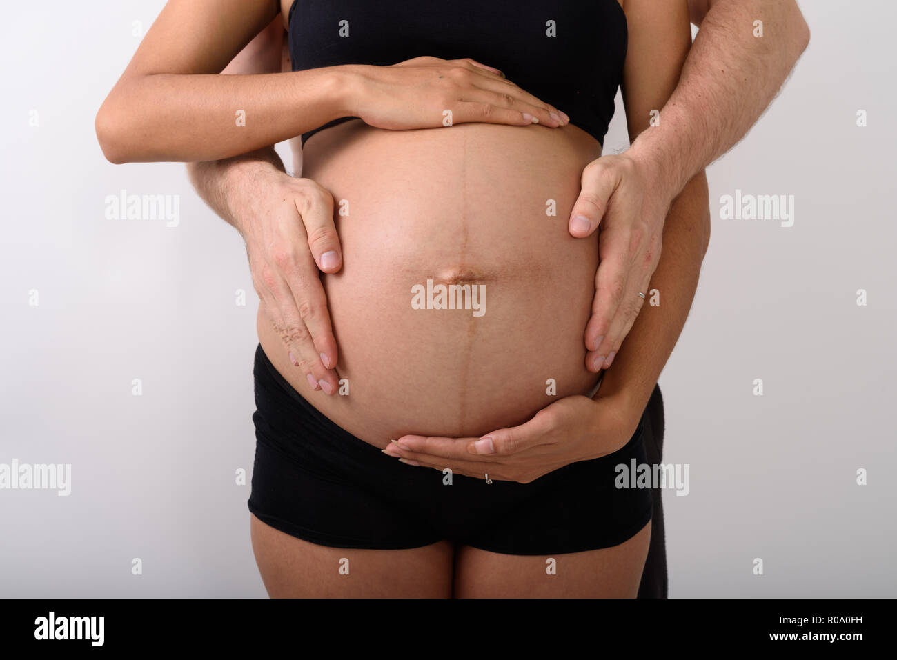 Asian donna incinta con l uomo mentre tiene il suo stomaco Foto Stock