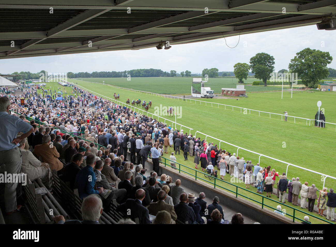 La folla di spettatori guarda un cavallo di razza in Thirsk racecourse nel North Yorkshire dalla tribuna e recinzione Foto Stock