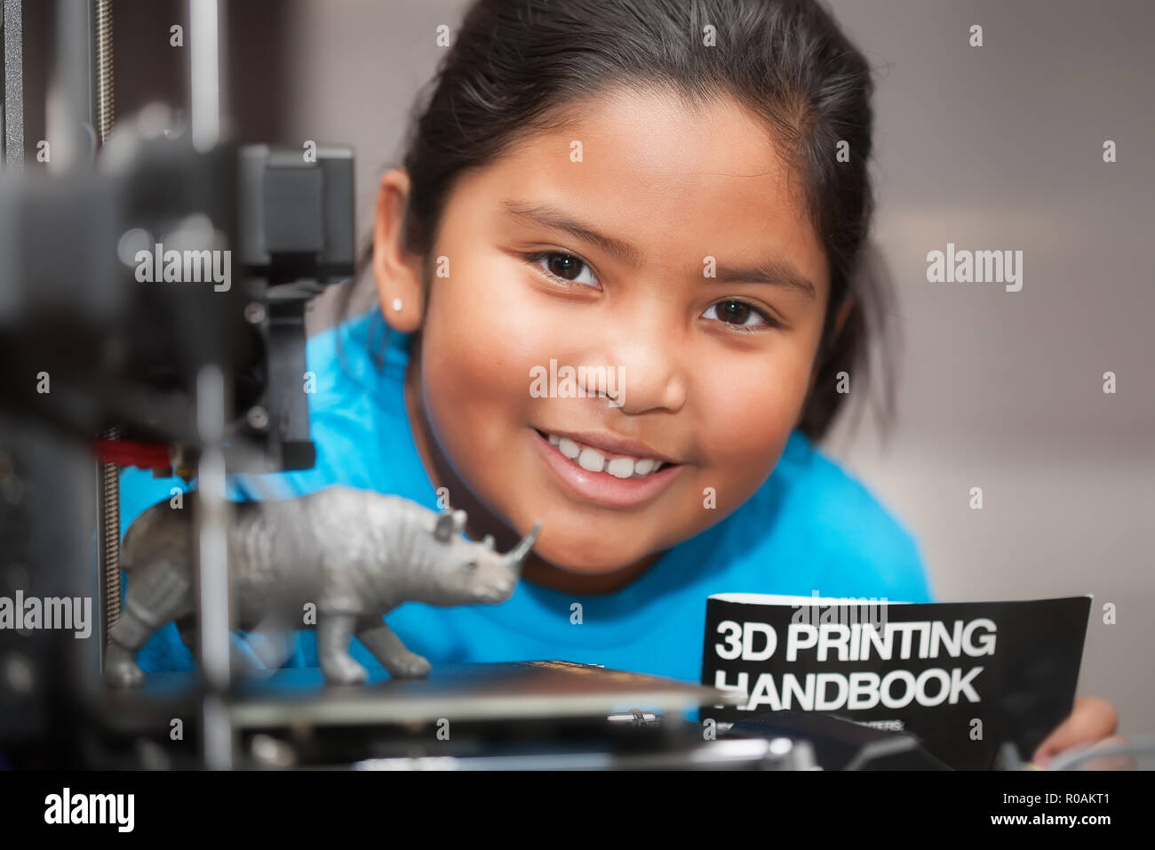 Un felice latino la ragazza è orgogliosa del suo 3d giocattolo stampato ed è in possesso di un 3d la stampa manuale come parte di un gambo summer camp. Foto Stock