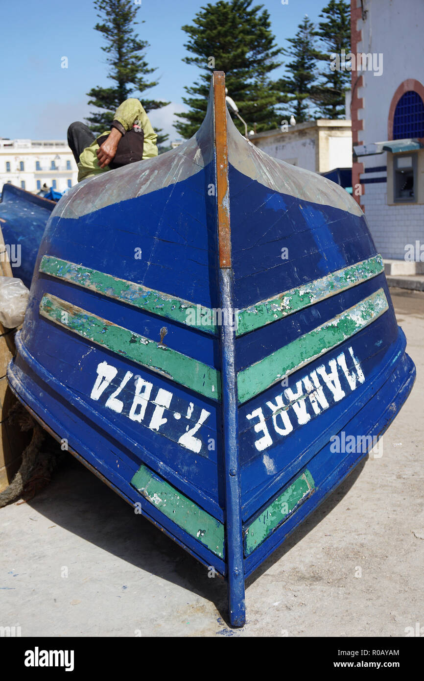 In legno di colore blu barca da pesca e dormire uomo, Essaouira, Marocco Foto Stock