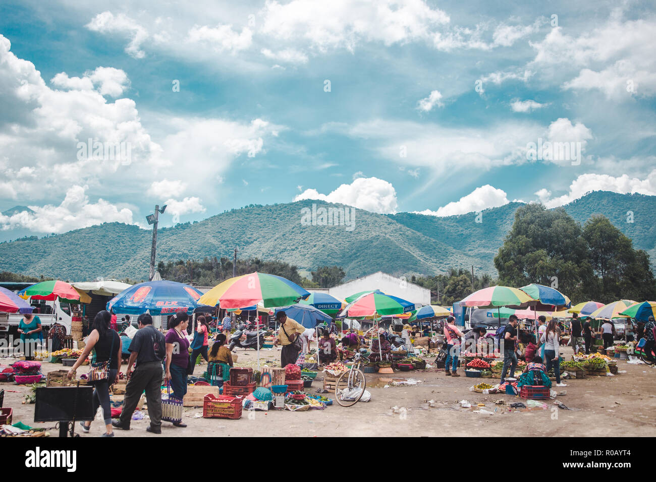 Cibo vivaci bancarelle del mercato prevista sul pavimento da donne nel tradizionale abito Maya sotto ombrellone colorati ombrelloni in Antigua, Guatemala Foto Stock