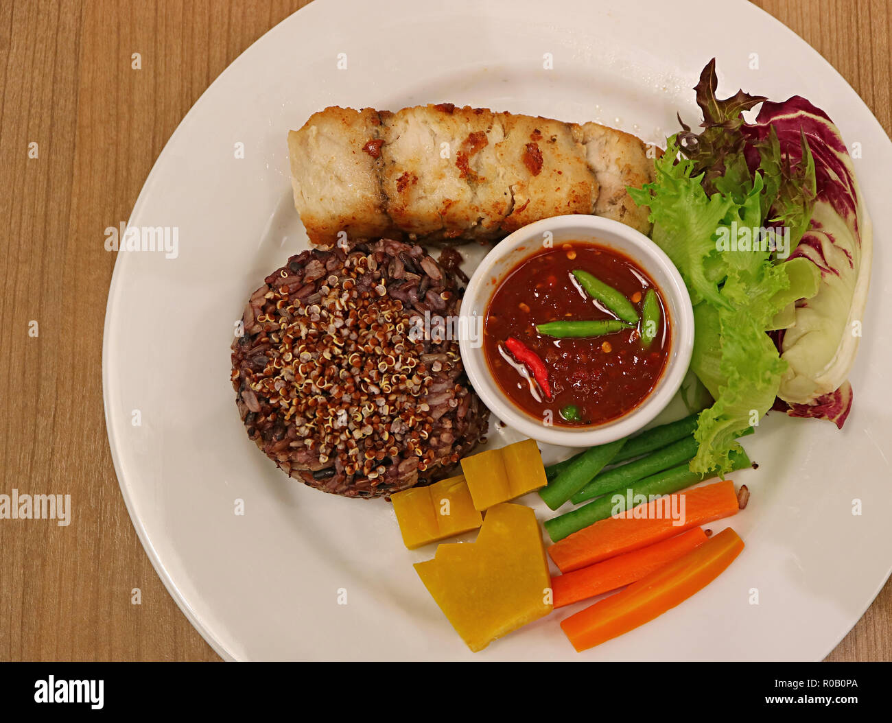 Vista dall'alto di stile tailandese riso al vapore-berry riso con la quinoa servita con grigliate di Bianco di branzino, freschi e verdure bollite, piccante Pasta Gamberi Dip Foto Stock