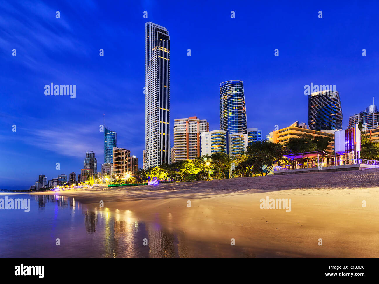 Australian Surfers Paradise City CBD lungo a lato della spiaggia di sunrise con la riflessione in oceano onde di grattacieli illuminati e Q1 alto-aumento accommodat Foto Stock