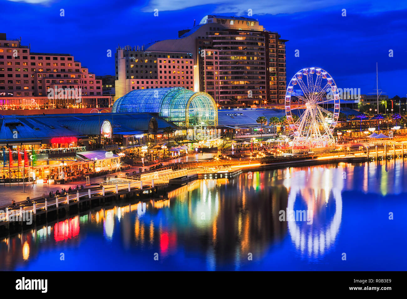 Ferries Wheel sul lungomare di Sydney Darling Harbour e harbourside area di intrattenimento con passerelle, café, hotel e alloggi a tramonto wi Foto Stock