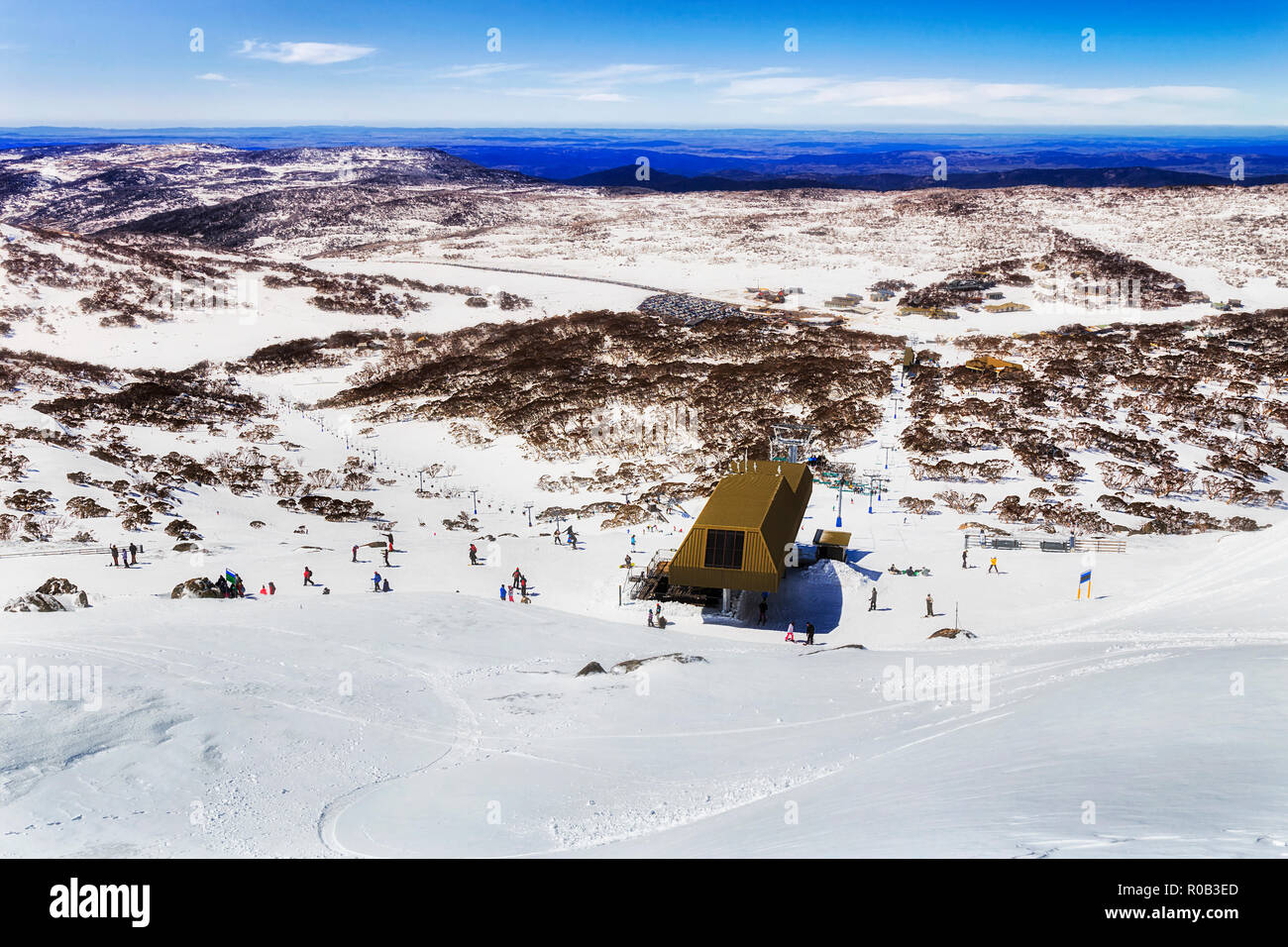 Dalla vetta del Monte Perisher indietro in alta montagna innevata di Australia guardando giù alla stazione della seggiovia per snowboarder e sciatori sopra Perisher va Foto Stock