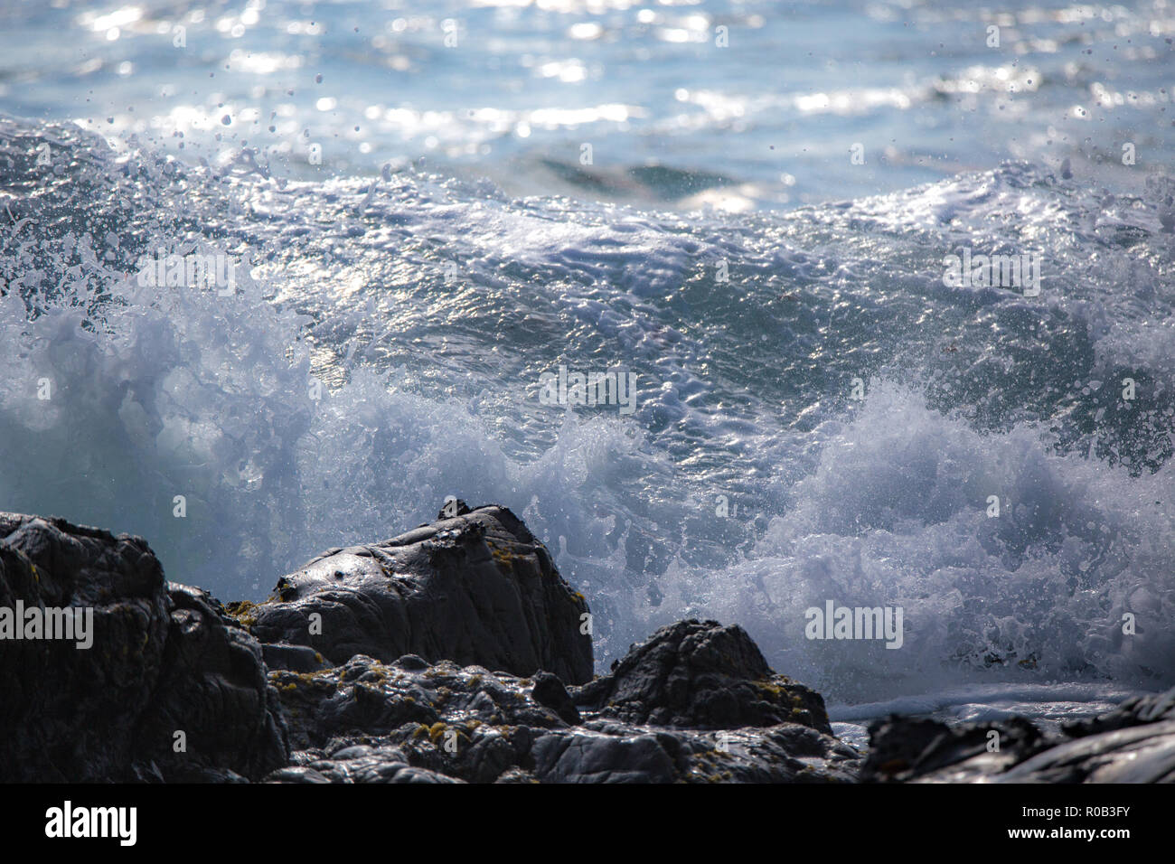 Le onde infrangersi e rottura sul litorale roccioso Foto Stock
