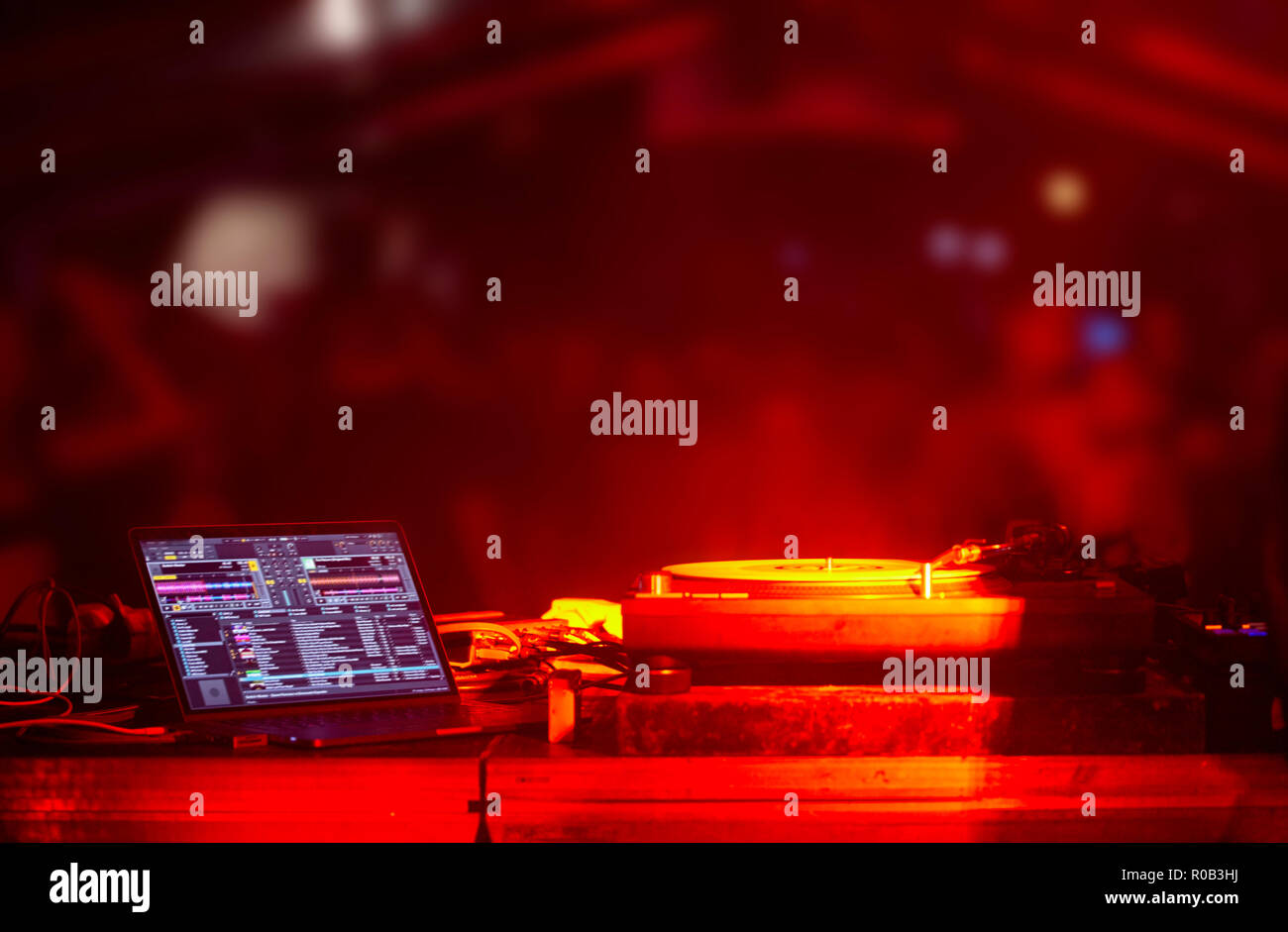 Parte dietro le quinte, cabina DJ giradischi apparecchiature computer, fuori fuoco blured folla, luci rosse. Foto Stock