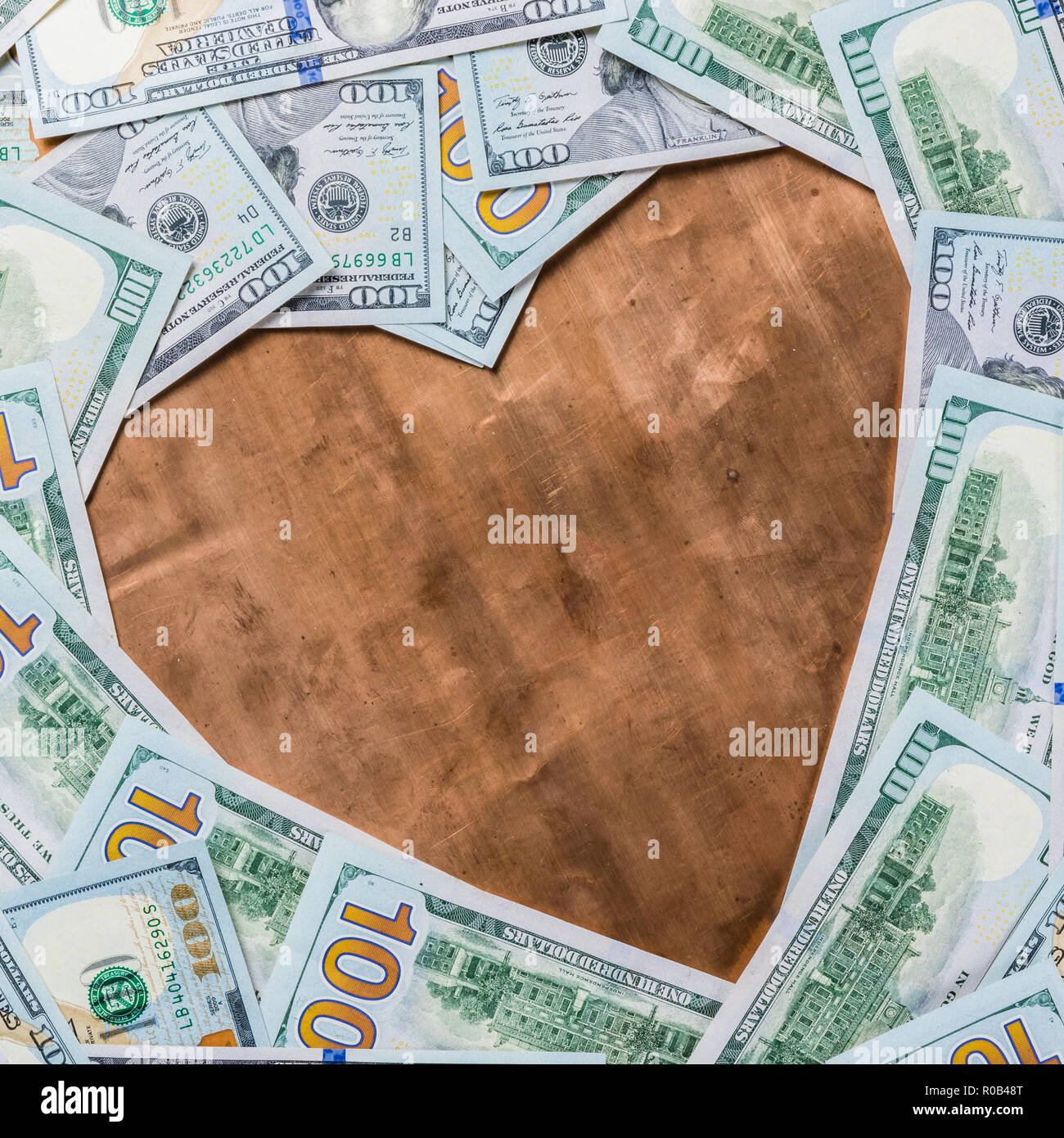 Bronzo rame forma di cuore nel centro del dollaro sullo sfondo di denaro da un centinaio di dollari Foto Stock