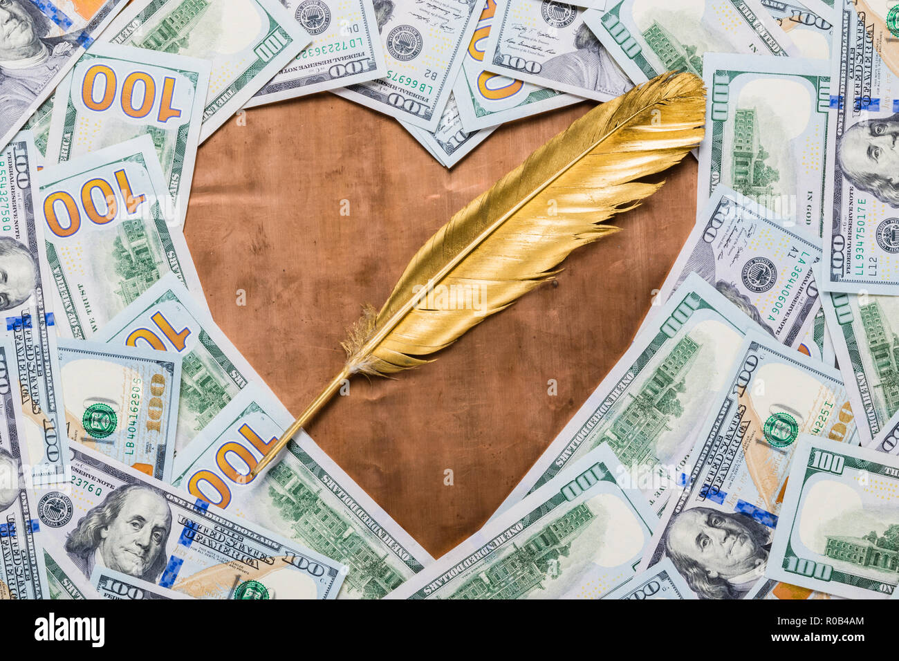Bronzo rame forma di cuore e gold quill penna nel centro del dollaro sullo sfondo di denaro Foto Stock