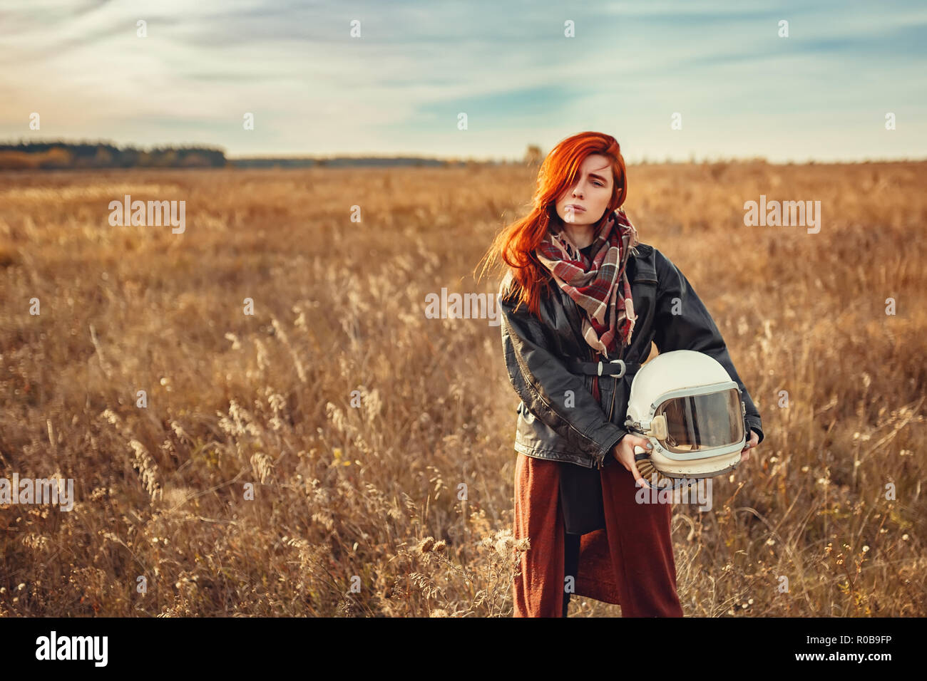 Giovane ragazza redhead in nero giacca di pelle e casco di volo all'aperto Foto Stock
