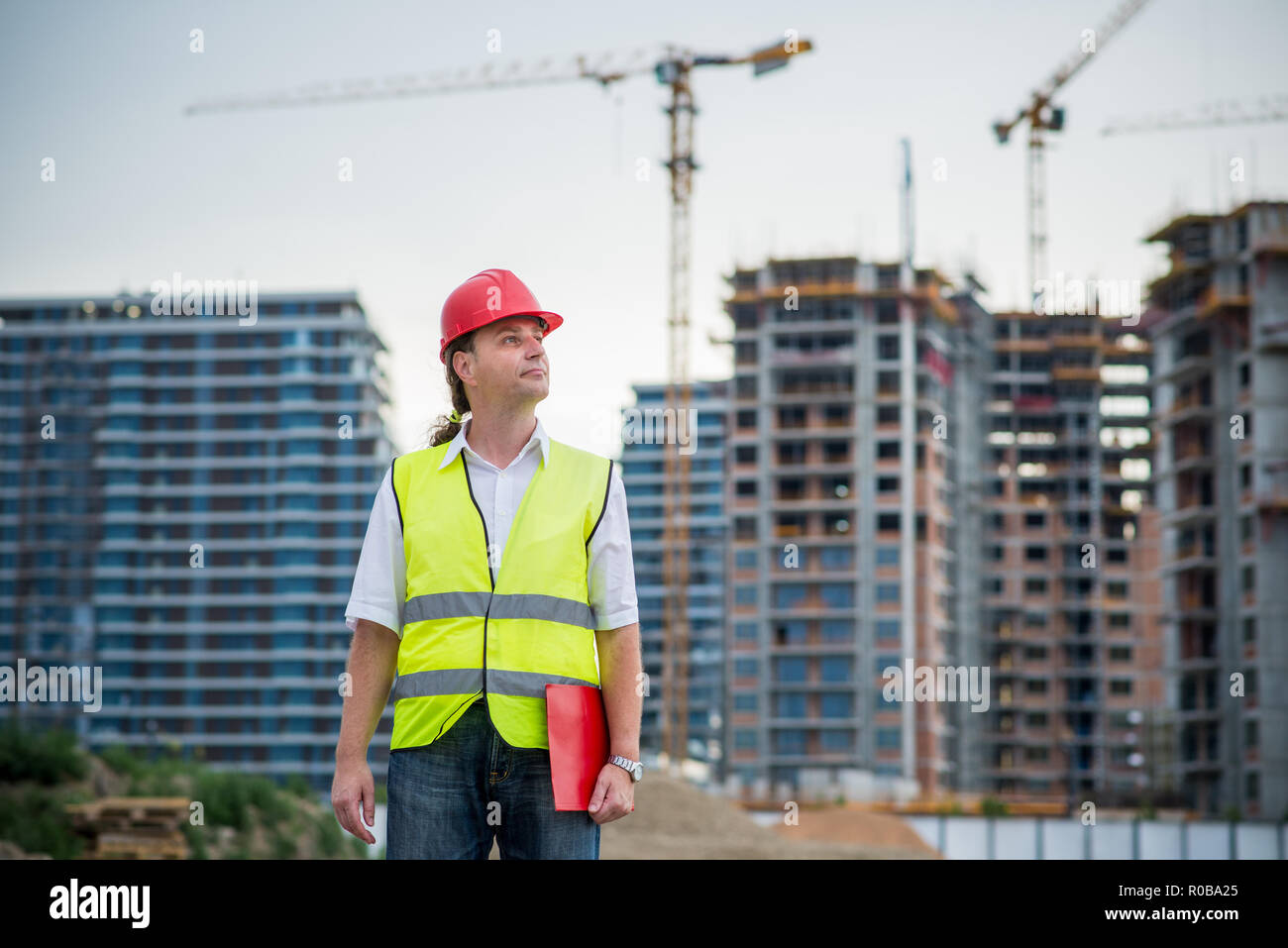 Tecnico su un sito in costruzione a lavorare sul progetto di alloggiamento Foto Stock