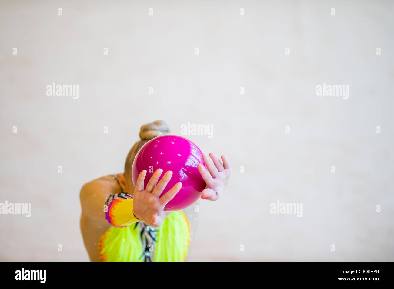 Ragazza con una ginnastica ritmica palla rosa. La flessibilità in acrobazie e fitness salute Foto Stock