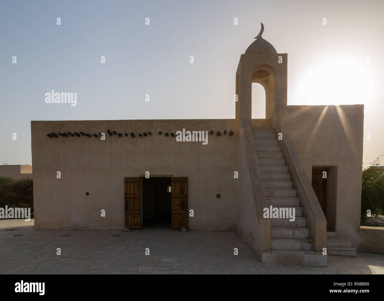 Retroilluminazione della sera silhouette di una vecchia moschea sul tramonto, Barzan torri di avvistamento site, costruita con pietra di corallo e calcare e antica moschea araba vicino a Umm Foto Stock