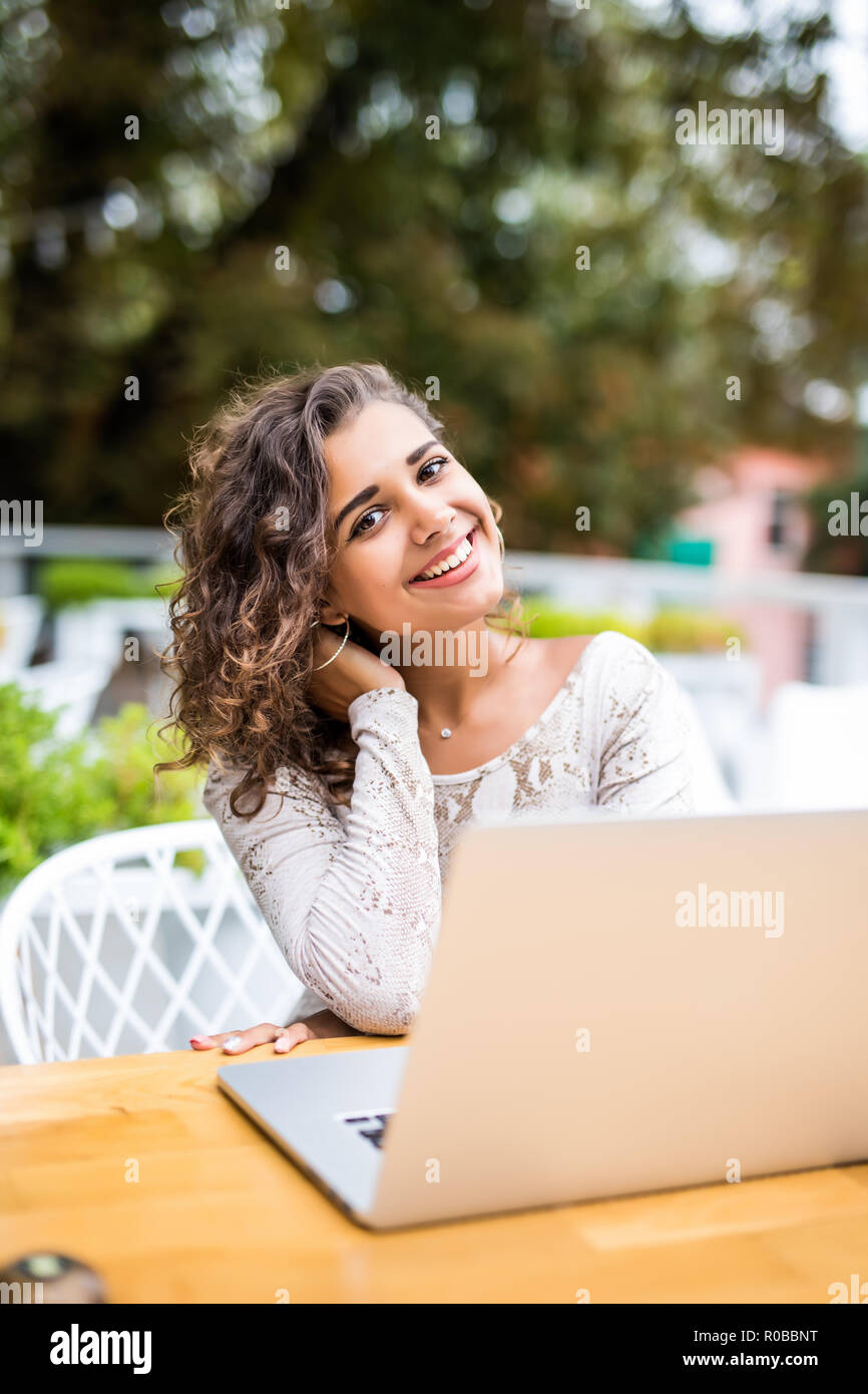 Bella giovane ricci donna latina con un'acconciatura afro lavorando al suo computer portatile in un coffee shop Foto Stock