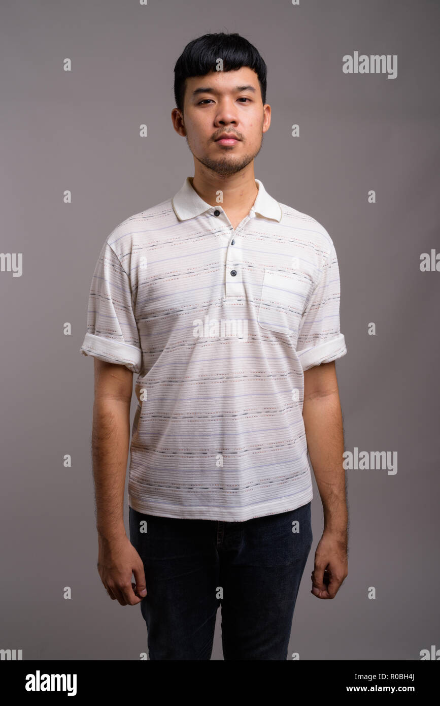 Ritratto di giovane uomo asiatico contro uno sfondo grigio Foto Stock