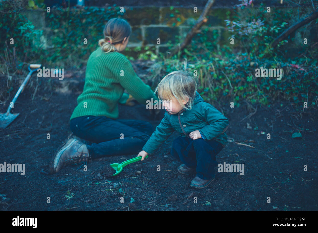 Una madre e bambino sono a scavare buche nel giardino in autunno Foto Stock