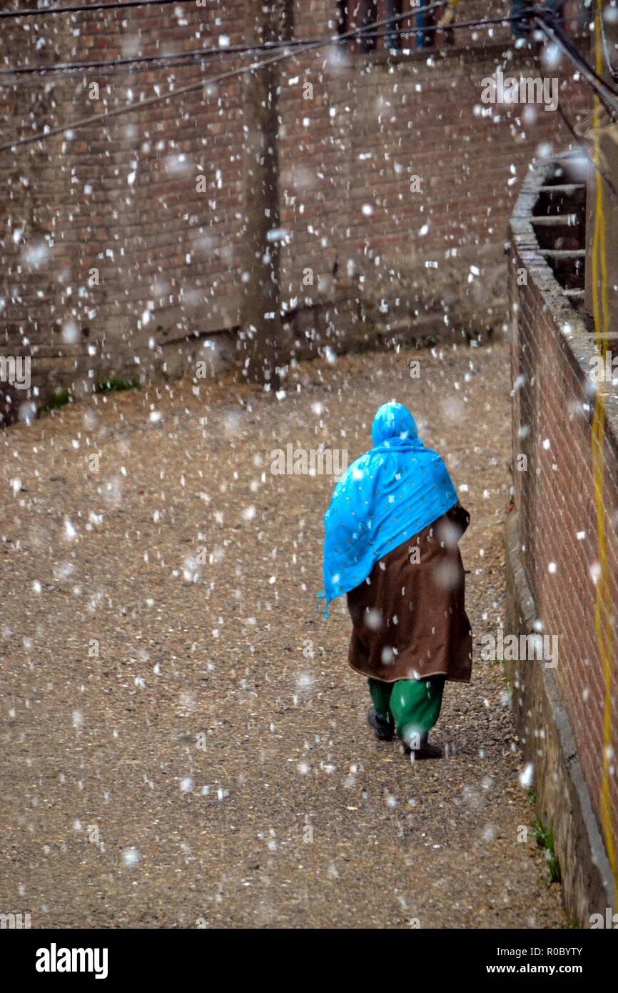 Una donna del Kashmir passeggiate durante le stagioni prima nevicata a Srinagar, Indiano Kashmir amministrato. Diritto all'avvento dell'inverno, Kashmir valley ha ricevuto la sua prima nevicata come ondata di freddo come le condizioni afferrata la valle a causa di continue acquazzone. Tutte le stazioni meteorologiche attraverso la valle venerdì assistito ad un calo di circa 10 gradi Celsius dalle normali temperature di giorno per questo periodo dell'anno. Foto Stock