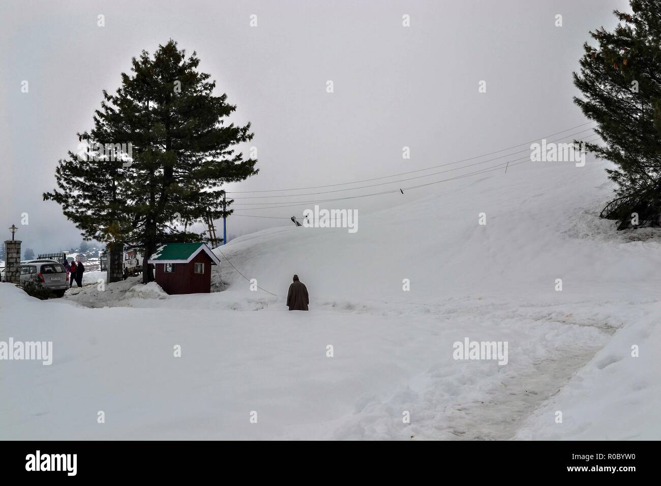 Un uomo cammina lungo una coperta di neve strada durante le stagioni prima nevicata in Gulmarg, a circa 55km da Srinagar, Indiano Kashmir amministrato.diritto all'avvento dell'inverno, Kashmir valley ha ricevuto la sua prima nevicata come ondata di freddo come le condizioni afferrata la valle a causa di continue acquazzone. Tutte le stazioni meteorologiche attraverso la valle venerdì assistito ad un calo di circa 10 gradi Celsius dalle normali temperature di giorno per questo periodo dell'anno. Foto Stock