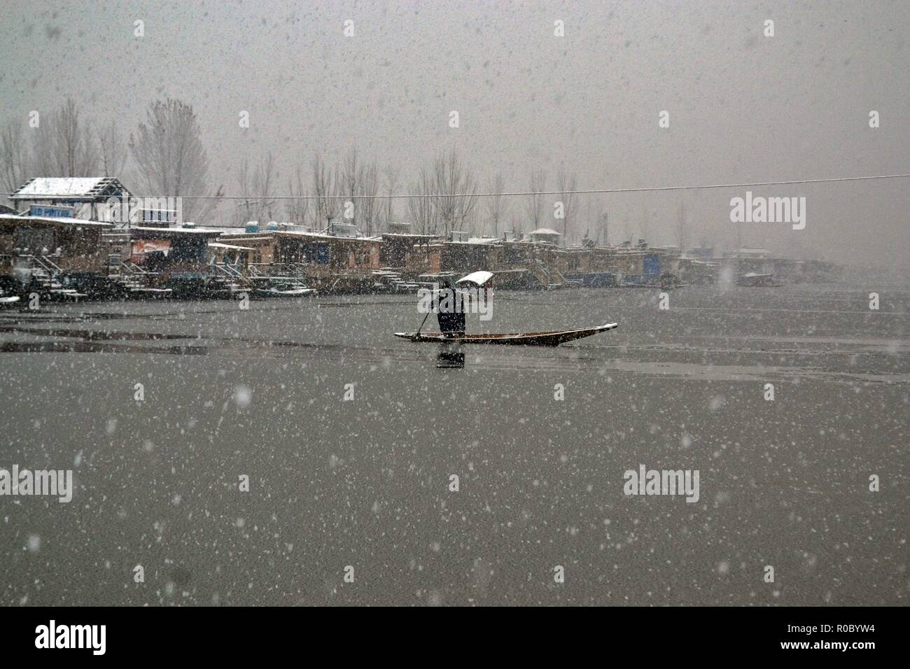 Un uomo righe la sua barca su Dal lago durante le stagioni prima nevicata a Srinagar, Indiano Kashmir amministrato. Diritto all'avvento dell'inverno, Kashmir valley ha ricevuto la sua prima nevicata come ondata di freddo come le condizioni afferrata la valle a causa di continue acquazzone. Tutte le stazioni meteorologiche attraverso la valle venerdì assistito ad un calo di circa 10 gradi Celsius dalle normali temperature di giorno per questo periodo dell'anno. Foto Stock