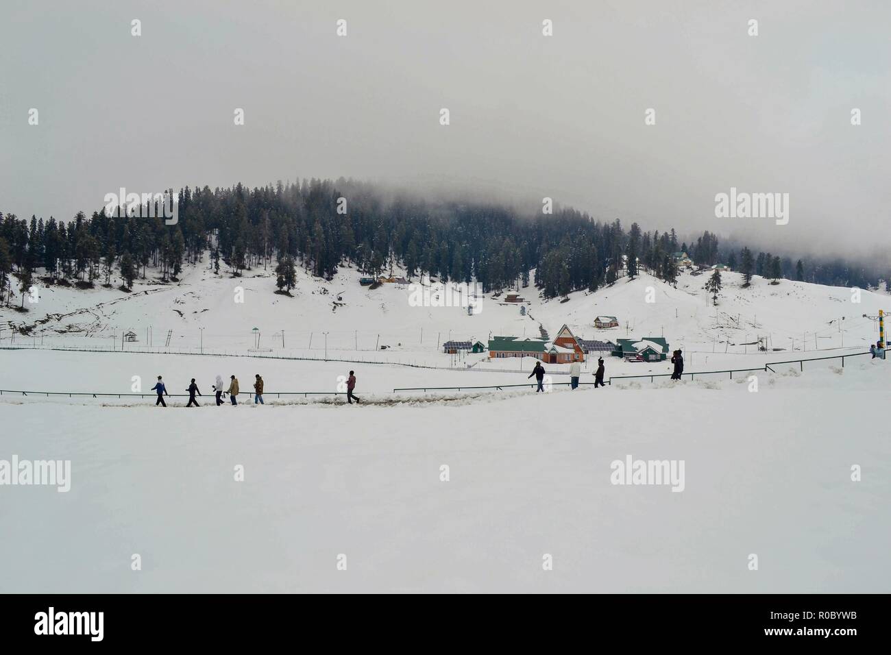 I turisti a piedi lungo una coperta di neve strada durante le stagioni prima nevicata in Gulmarg, a circa 55km da Srinagar, Indiano Kashmir amministrato. Diritto all'avvento dell'inverno, Kashmir valley ha ricevuto la sua prima nevicata come ondata di freddo come le condizioni afferrata la valle a causa di continue acquazzone. Tutte le stazioni meteorologiche attraverso la valle venerdì assistito ad un calo di circa 10 gradi Celsius dalle normali temperature di giorno per questo periodo dell'anno. Foto Stock
