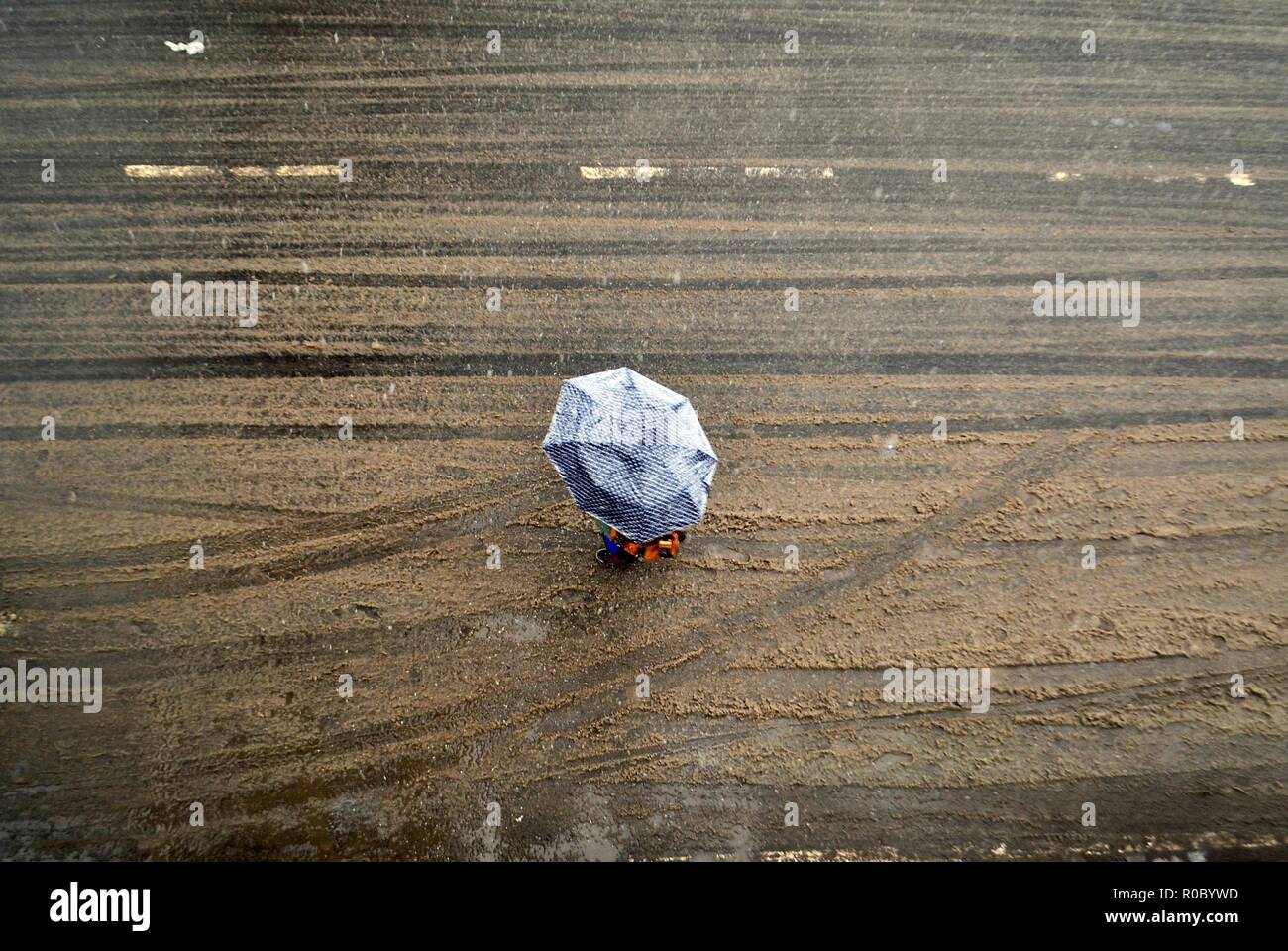 Un residente con un ombrello passeggiate durante le stagioni prima nevicata a Srinagar, Indiano Kashmir amministrato. Diritto all'avvento dell'inverno, Kashmir valley ha ricevuto la sua prima nevicata come ondata di freddo come le condizioni afferrata la valle a causa di continue acquazzone. Tutte le stazioni meteorologiche attraverso la valle venerdì assistito ad un calo di circa 10 gradi Celsius dalle normali temperature di giorno per questo periodo dell'anno. Foto Stock