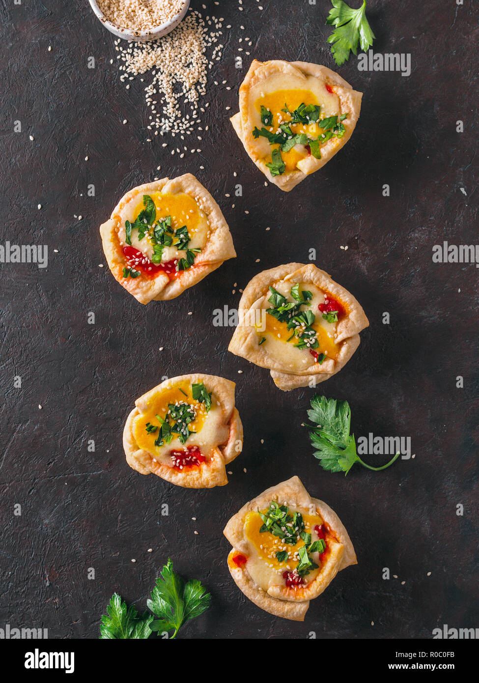 Idee e ricette per una sana vegane Shakshouka tazze con tofu vegan uova e la curcuma tuorlo. Sfoglia di pasta filo,la salsa di pomodoro e il prezzemolo verde.vista superiore o piatta lay.Copia spazio per il testo. Verticale. Foto Stock