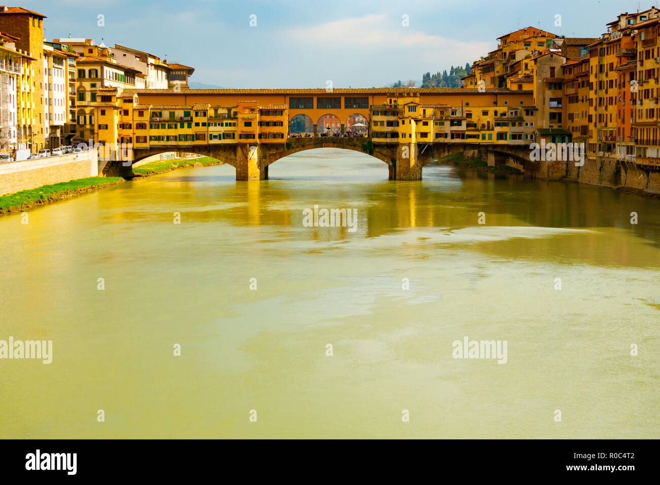 Vista frontale in caldi colori della pietra medievale Ponte Vecchio oltre il fiume Arno visto dalla Santissima Trinità bridge, Firenze, Toscana, Italia. Foto Stock