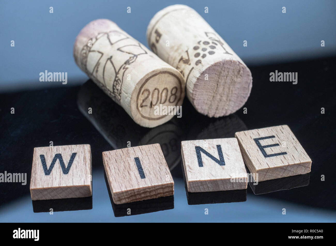 Due tappi accanto a un paio di lettere di legno con la parola vino Foto Stock