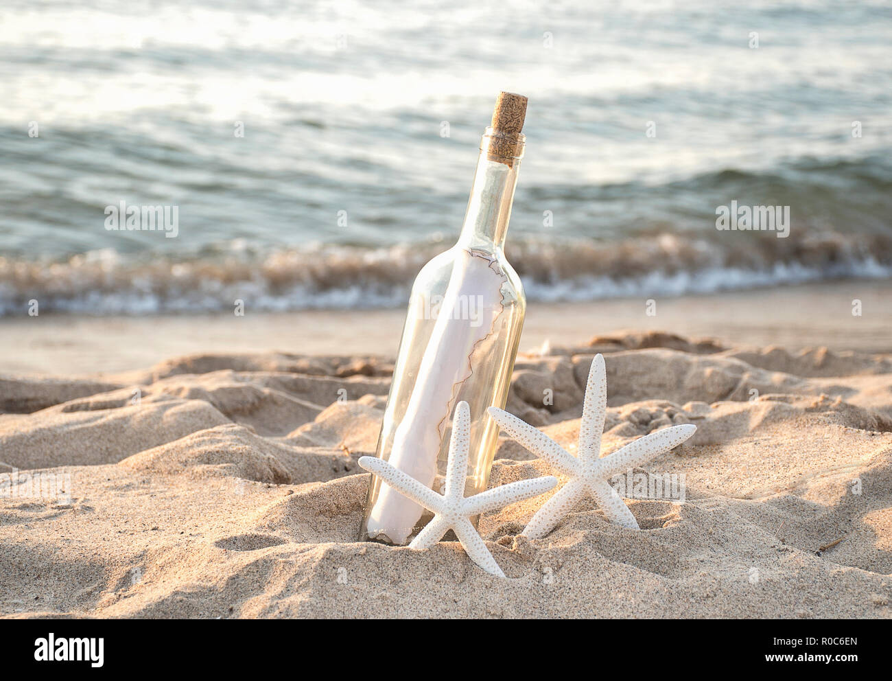 Coppia di bianco tropicale stella di mare nella spiaggia di sabbia con la carta un messaggio in bottiglia Foto Stock